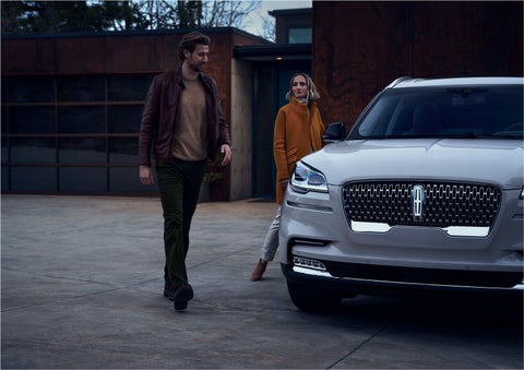 A man and a woman approaching a 2023 Lincoln Aviator® SUV, which illuminates certain lights when they are close | Spitzer Lincoln DuBois in Du Bois PA