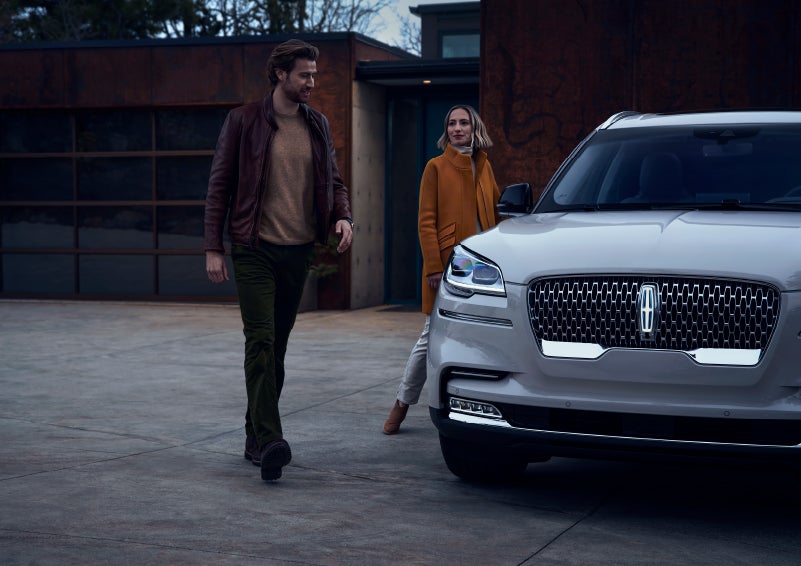 A man and a woman approaching a 2024 Lincoln Aviator® SUV, which illuminates certain lights when they are close | Spitzer Lincoln DuBois in Du Bois PA