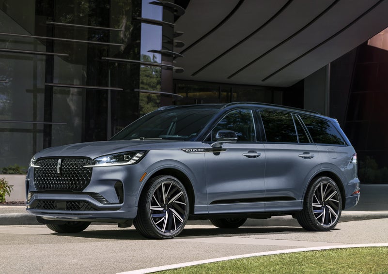 A gray 2025 Lincoln Aviator® SUV is parked outside a modern building showcasing the driver’s side of the vehicle. | Spitzer Lincoln DuBois in Du Bois PA