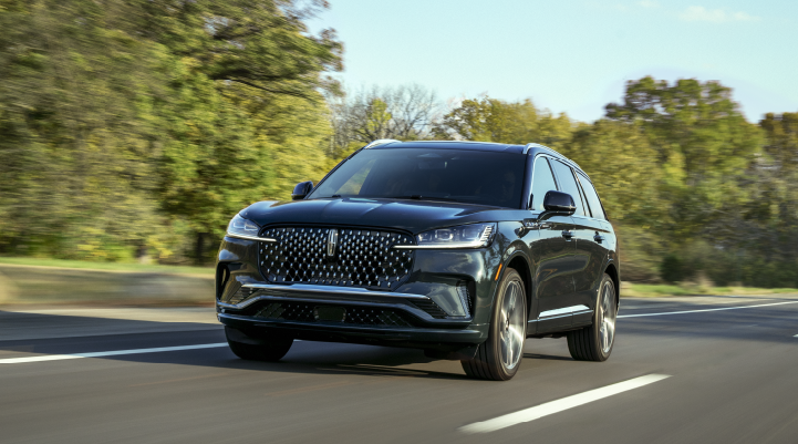 A 2025 Lincoln Black Label Aviator® SUV is being driven down a road lined with trees. | Spitzer Lincoln DuBois in Du Bois PA