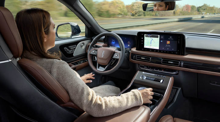 A woman is seen sitting in the driver’s seat of her 2025 Lincoln Aviator® SUV with her hands off the steering wheel. | Spitzer Lincoln DuBois in Du Bois PA