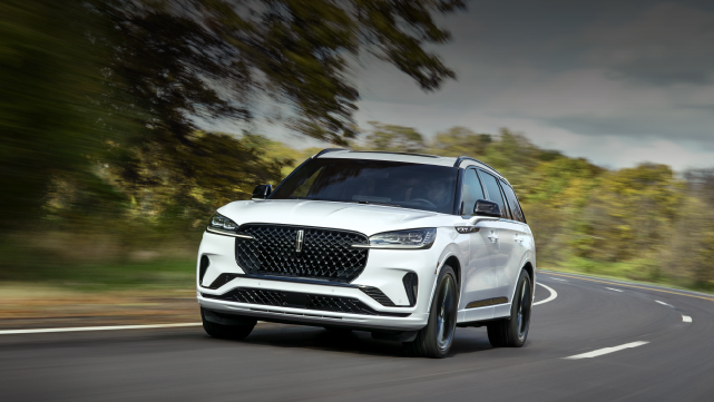 A white 2025 Lincoln Aviator® SUV is being driven down a road lined with trees. | Spitzer Lincoln DuBois in Du Bois PA