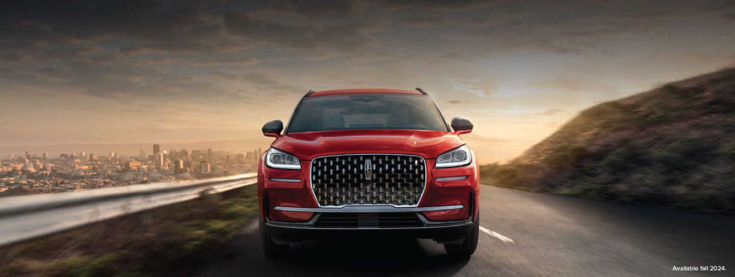 A 2025 red Lincoln Corsair® SUV is being driven down a road at sunset. | Spitzer Lincoln DuBois in Du Bois PA