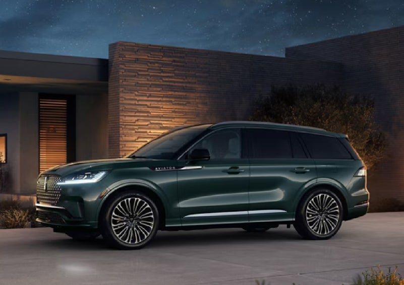 A green 2027 Lincoln Aviator® SUV is parked outside a contemporary home. | Spitzer Lincoln DuBois in Du Bois PA