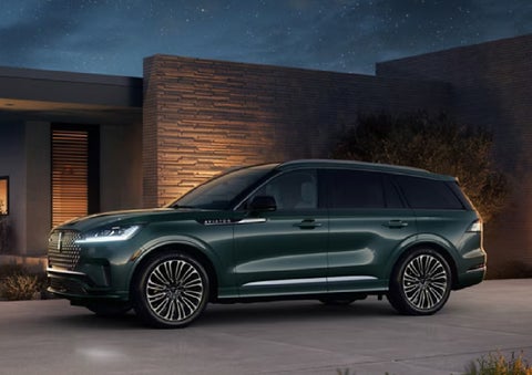 A green 2027 Lincoln Aviator® SUV is parked outside a contemporary home. | Spitzer Lincoln DuBois in Du Bois PA