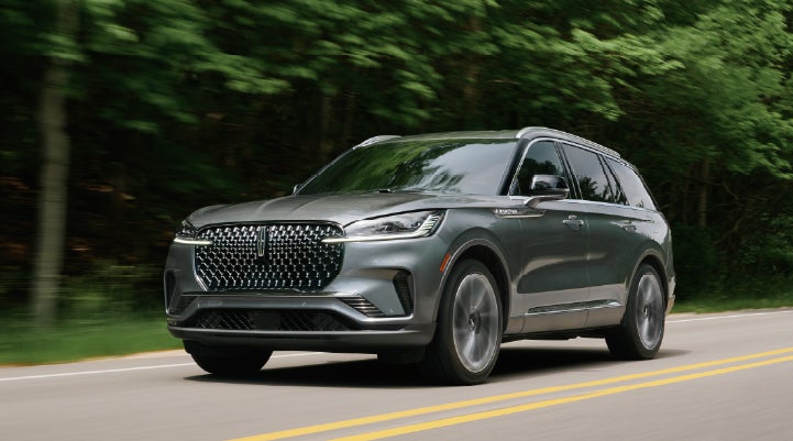 A 2027 Lincoln Aviator® SUV is being driven down a road lined with trees. | Spitzer Lincoln DuBois in Du Bois PA